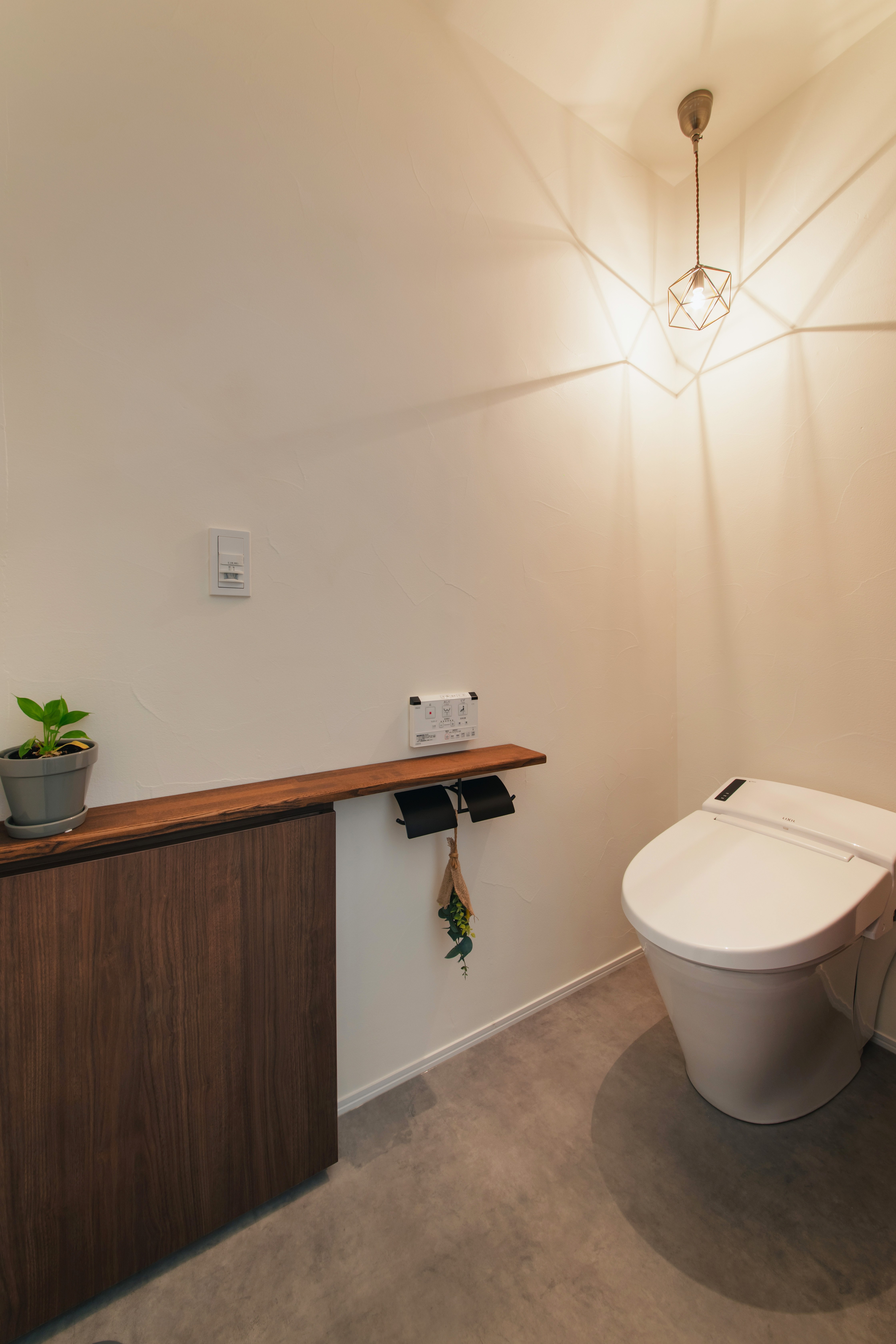 壁の中のデッドスペースを上手く使い、薄くすっきりとした収納を・・・。 トイレの内の雰囲気もこだわり陰影が素敵なペンダント照明を採用